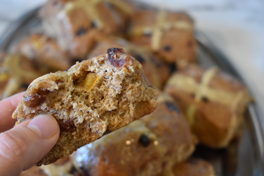 A soft and fluffy sourdough hot cross bun with a bite taken out of it